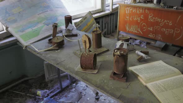 Rusty Cans And Open Book On Top Of The Dusty Table Inside The Classroom Of Abandoned School In Chern alt