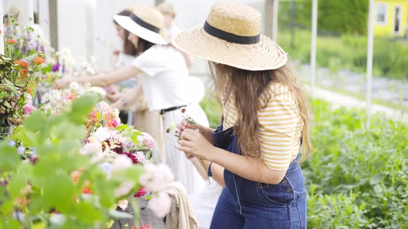 Lady in Hat Chooses Flowers From Vases at Masterclass