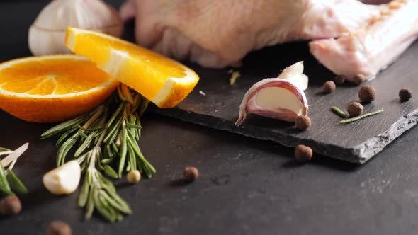 Raw Organic Whole Duck with Cut Orange and Rosemary on Slate Board on Black Background alt