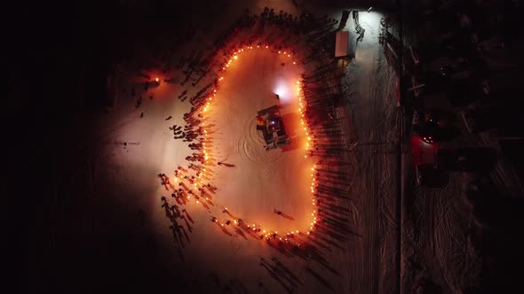 Aerial Over Crowd Of People On Ski Slope With Torchlights