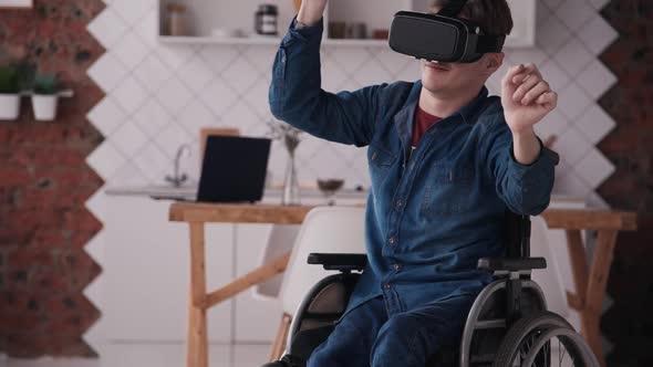 Young Man in Wheelchair Using Virtual Reality Helmet at Home
