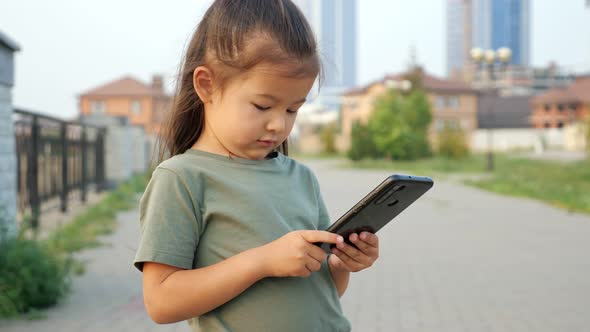 Annoyed Asian Girl Presses Stuck Keys on Phone on Waterfront alt