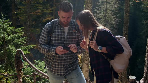 Male and Female Backpackers are Viewing Electronic Map in Smartphone Walking in Natural Park alt