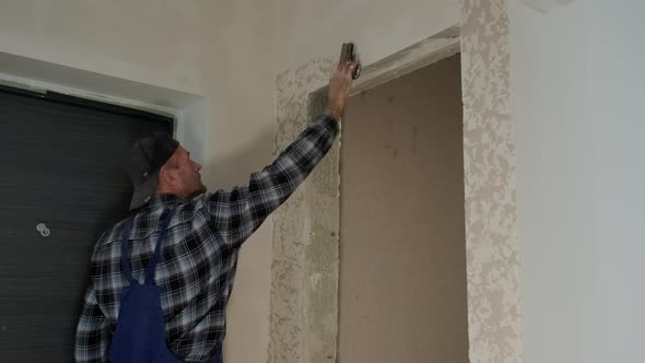 Wide View Footage of Worker Puts Decorative Plaster on the Wall Forming a Relief alt