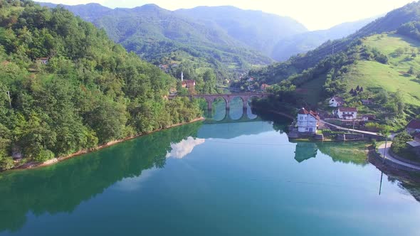 Flying over river and old stone bridge in Bosnia