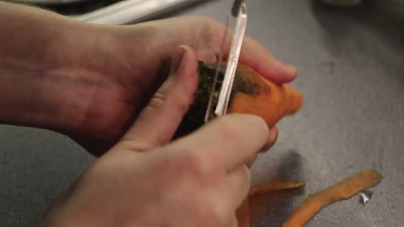 A view of the hands of a woman who peels carrots in the kitchen. film grain alt