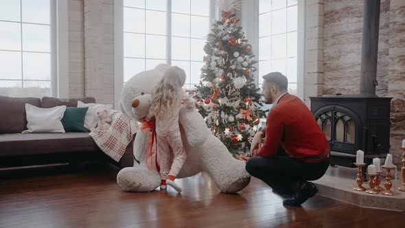 Girl Happy to Get a Giant Teddy Bear Hugging with Father on Christmas Morning alt