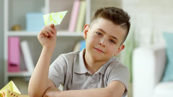 Portrait of Happy Little Boy Posing for Camera with Handmade Origami Boat alt