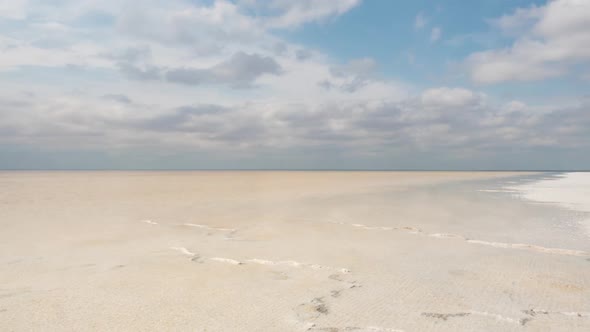 The beach of the salt lake with clouds reflected in the smooth water.