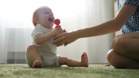 Mother and Baby Playing with Toys on a Carpet at Home