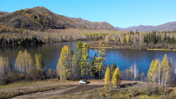 The car drives along a country road along the blue Yenisei River.