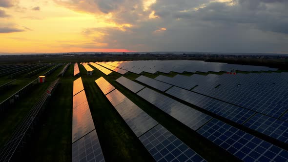 Aerial top view of Solar Power Station at Sunset. Flying above panels in a row in the fields. alt