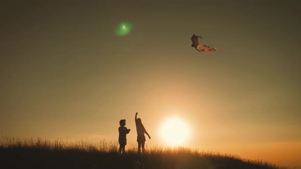 Two Children Launch a Kite in the Field at Sunset alt