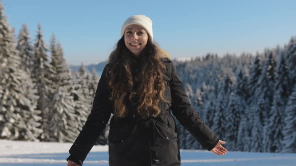 Woman Portrait Looking at Camera and Smiling on a Sunny Winter Day in the Snowy Forest alt