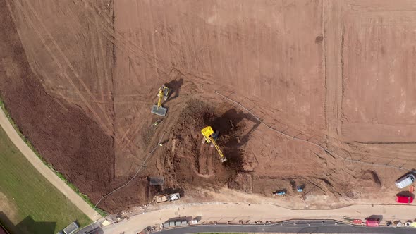 Aerial view of escavator at work on red soil to build new houses in England