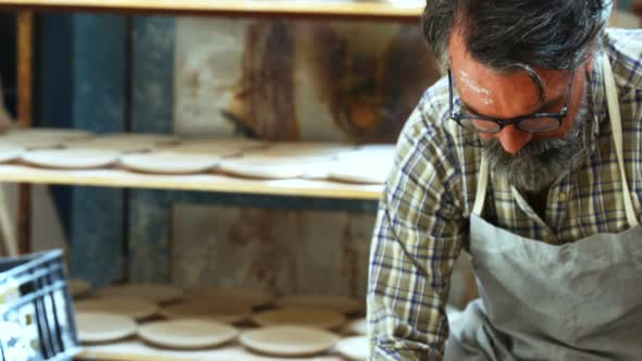Male potter scrapping out the extra clay from the ceramic bowl 4k alt