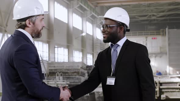 Multiracial business partners signing document at factory