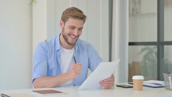 Young Creative Man Celebrating Success While Reading Documents alt