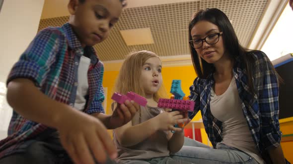 Teacher with Diverse Kids Playing with Didactic Toys alt