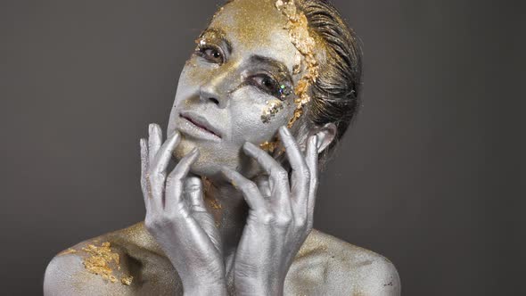 Beautiful Young Female Model with Gold and Silver Paint on Her Skin and Hair in the Studio