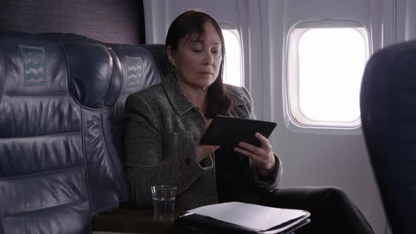 Businesswoman using digital tablet on airplane