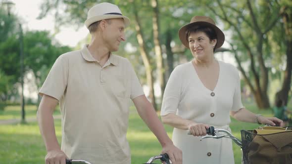 Handsome Mid-adult Man Kissing Wife on Cheek and Talking with Loving Spouse. Portrait alt