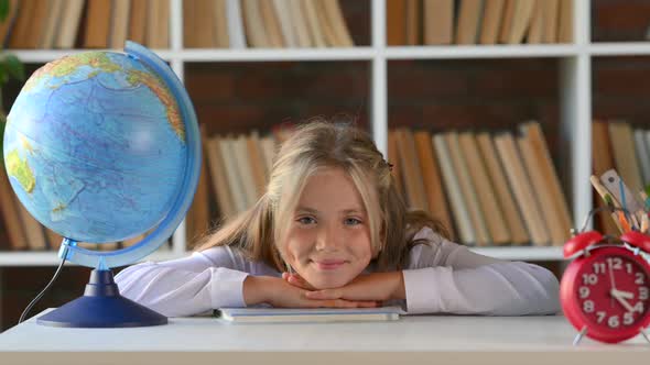 Portrait of a young hispanic schoolgirl primary school student sitting at her desk