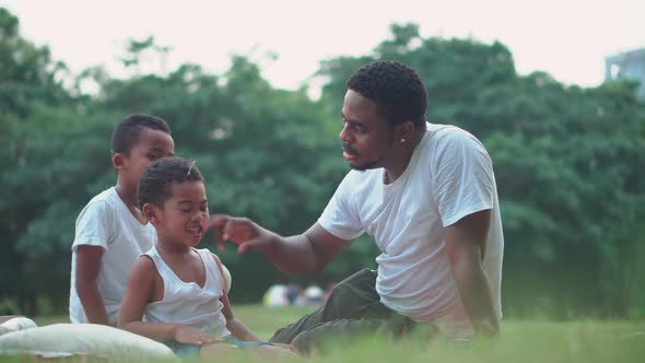 Dark sons and dad playing in park, African American father and two son play in park