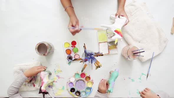 Step by step. Little girls painting paper mache unicorn with acrylic paint. alt