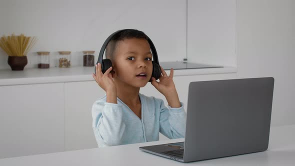 Cute Little Black Boy Wearing Wireless Headphones Listening Music Online On Computer alt
