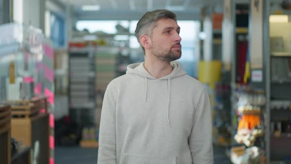 Handsome Concentrated Man Looking Around Standing in Hardware Store and Thinking alt