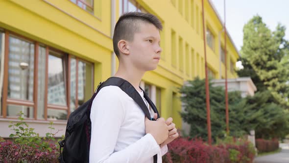 A Caucasian Teenage Boy Looks Around As He Waits for Something  Side View  a School