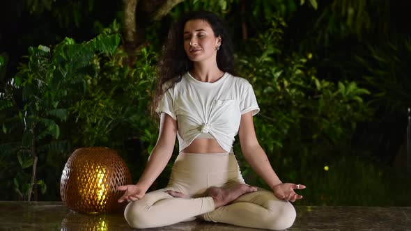 Brunette Woman Enjoys Yoga in Lotus Position in Evening