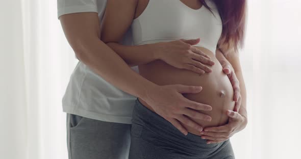 Close Up happy Asian husband with a pregnant wife holding her belly.