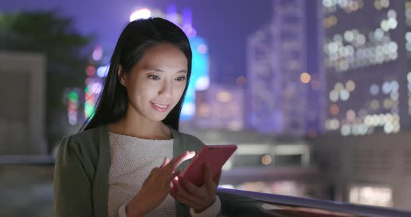 Woman sending message on cellphone in Hong Kong at night alt