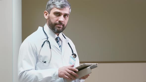 Male doctor with tablet computer in hospital hallway