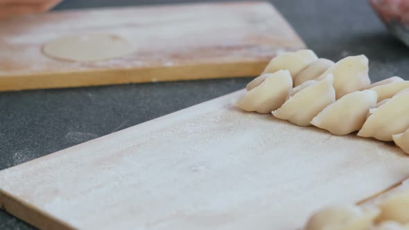 Woman Makes Dumplings with Mince Meat, Close-up Hands. Puts Dumplings on Wooden Board