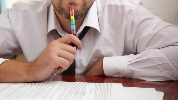 Man With A Beard In The Office With A Tie And A Suit Works, Fills Out Documents With A Pen