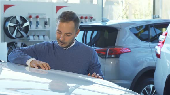 Business Man Examines the Car in the Car Showroom alt