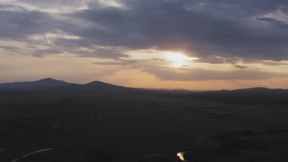 Drone View of a Sunset in a Valley with a River and Mountain Ranges alt