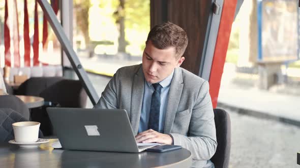 Business Man in Suit Using a Laptop in Cafe alt