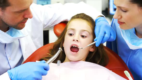 Dentists examining a young patient with tools alt