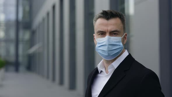 Portrait of Male Ceo Executive in Medical Mask Turning Head and Looking To Camera alt