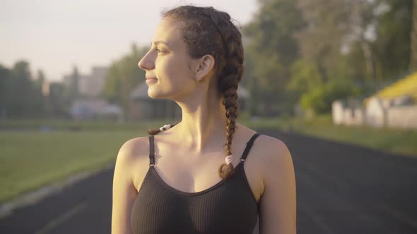 Beautiful Young Sportive Woman Looking at Sunrise and Turning To Camera. Portrait of Confident alt