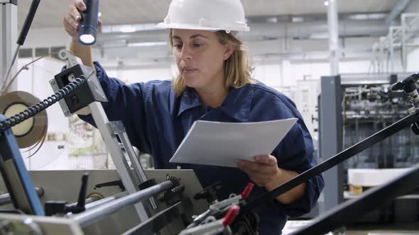 Concentrated Female Engineer Checking Mechanism with Flashlight alt