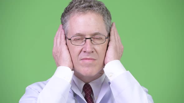 Portrait of Mature Man Doctor Covering Ears As Three Wise Monkeys Concept