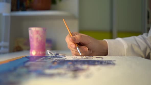 a girl draws a drawing with a brush close-up side view