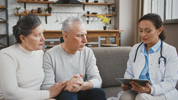 Woman Doctor Saying Diagnosis to Confused Senior Male Sitting on Couch During Medical Consultation alt
