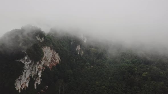 Flying From the Clouds to the Earth Above Tropical Valley with Mist on a Rainy Day