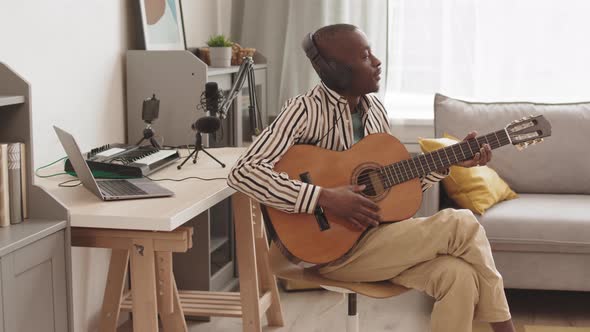 African Guitarist Wearing Headphones Playing Acoustic Guitar alt
